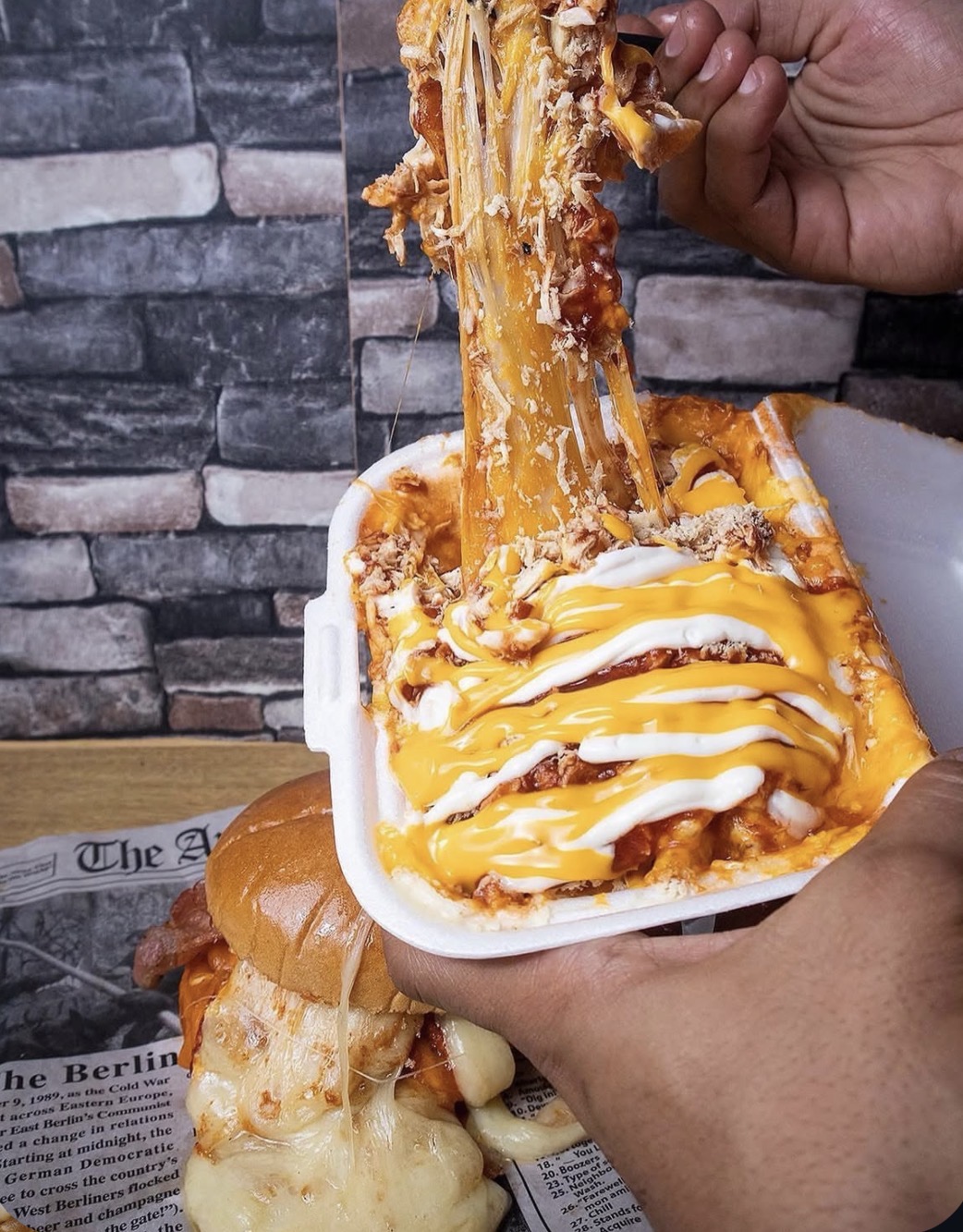 Loaded cheesy fries with pulled chicken in a takeout box