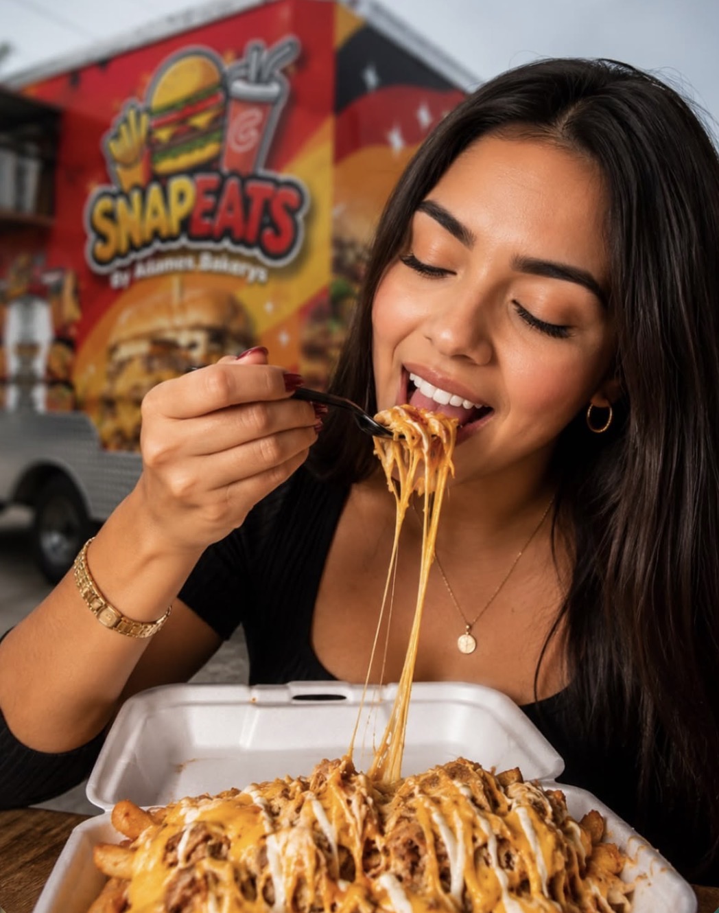 Guest eating cheesy loaded fries in front of the SnapEats trailer